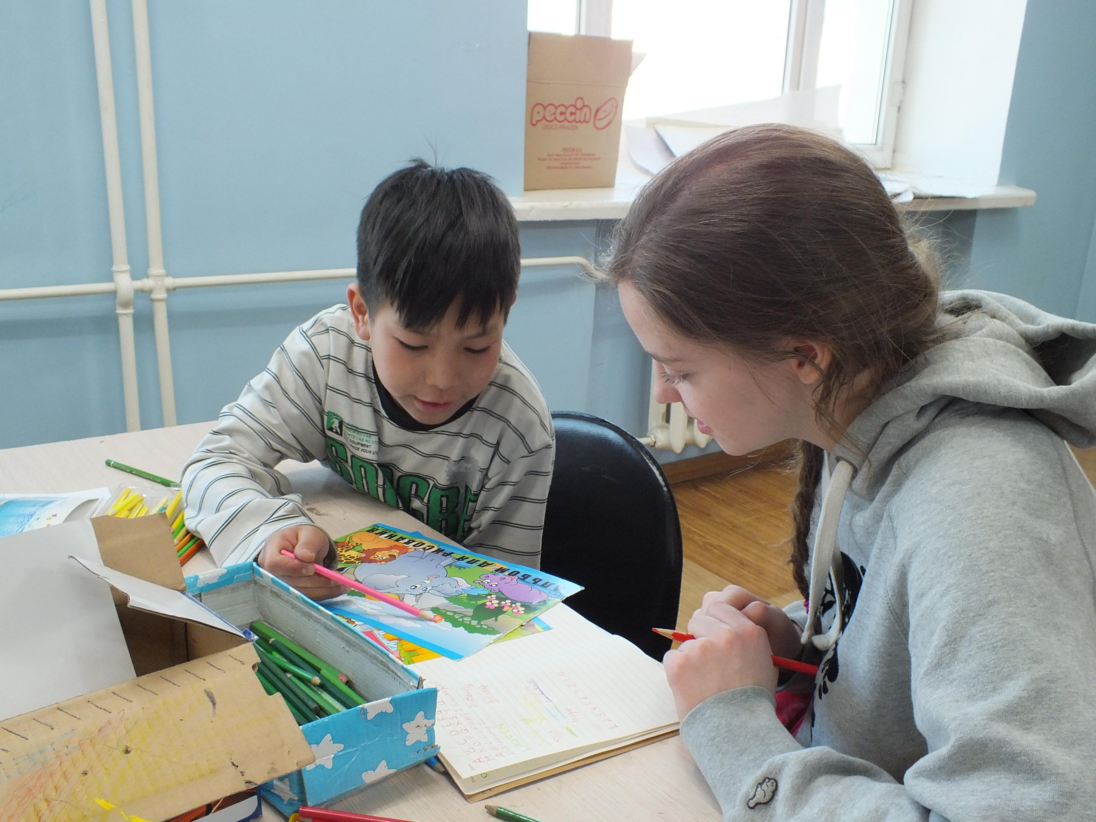 A Projects Abroad Social Work intern in Mongolia works on a colouring exercise with a child An intern works on a colouring activity during her Social Work internship in Mongolia